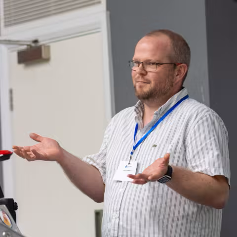 Ru gesturing with his hands whilst giving a talk in a lecture room.  (Photo credit Paul Johnson)